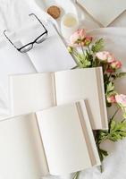 öppnade böcker och blommor ovanifrån på vit säng. håna design