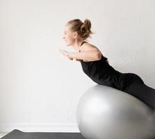 sportig kvinna som sitter på fitnessbollen värmer upp före träningspasset