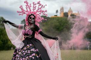 förtjusande catrina en dia de los muertos fotografering i cholulas cempasuchil fält, inramade förbi de ikoniska kolula kyrka fira skönhet tradition och de förtjusande rosa rök foto