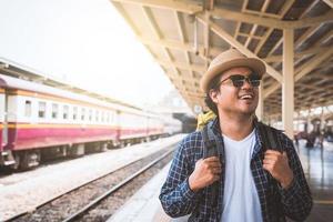 ung asiatisk resenärsryggsäck i tågstationen foto