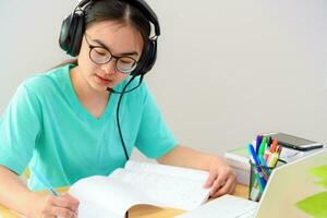 asiatisk kvinna skrivning anteckningar på bok inlärning uppkopplad foto
