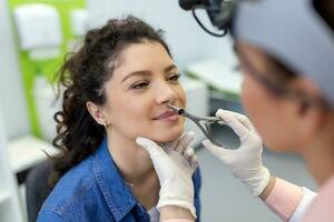 otolaryngology begrepp. positiv kvinna otorhinolaryngolog kontroll näsa med otoskop av hans patient på sjukhus. nasal trängsel, bihåleinflammation, allergi begrepp. kvinna patient på modern ent klinik. foto