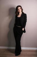självsäker affärskvinna som står i full längd i svart kostym foto