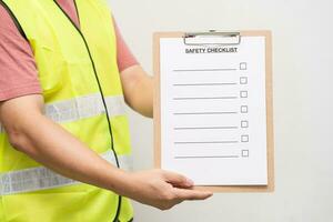 personal innehav tom kontroll på säkerhet checklista form. hand av personal är använder sig av de säkerhet checklista ark till kontrollera arbetssätt tillstånd i isolerat bakgrund. foto