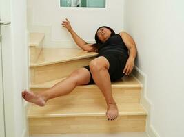 asiatisk lady kvinna skada från faller ner på hal ytor trappa på Hem. foto