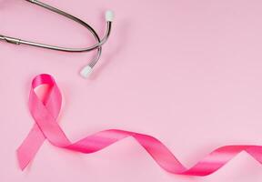 rosa band och stetoskop på färgad bakgrund. bröst cancer medvetenhet månad. kvinnors hälsa vård begrepp. symbol av bekämpa mot onkologi. foto