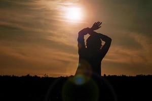 kvinna som njuter av solnedgången. kvinnlig siluett i fältet vid solnedgången foto