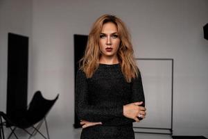 vacker kvinna på svart klassisk klänning poserar i studion foto