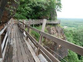 trä- bro i de skog, trä- gångväg på sandsten bergen på phu thok tempel, thailand, skön landskap av trä- väg längs de klippa foto