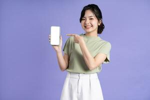 porträtt av skön asiatisk kvinna använder sig av smartphone på lila bakgrund foto