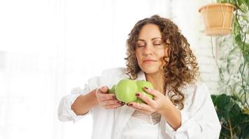 vacker ung kvinna som luktar ett äpple foto