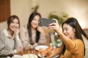 asiatisk syster vänner framställning selfie och leende med smartphone. fira med födelsedag kaka. foto