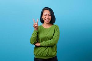 glad asiatisk kvinna som visar fredstecken på blå bakgrund foto