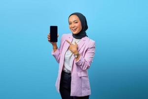 porträtt av leende asiatisk kvinna som visar smartphone tom skärm foto