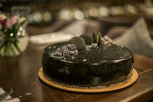 svart choklad kaka på en trä- tabell. dekorerad med choklad chip småkakor födelsedag kaka på en restaurang foto