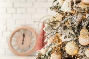 en jul ängel på de grenar av en jul träd mot de bakgrund av en klocka som visar 12. ny år eve 2022 firande foto