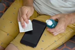 rengör din mobiltelefon med alkohol för att förhindra bakterier. foto