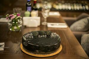 svart choklad kaka på en trä- tabell. dekorerad med choklad chip småkakor födelsedag kaka på en restaurang foto