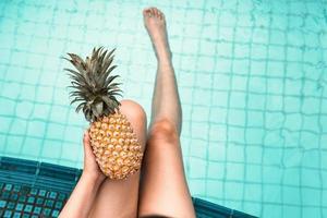 kvinna kopplar av i poolen medan hon håller ananas foto