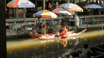 ratchaburi stad, rb, 2022- thai munkar ridning en båt för allmosa i de morgon- på gammal resa destination av thailand damnoen saduak flatning marknadsföra, ratchaburi thailand. foto