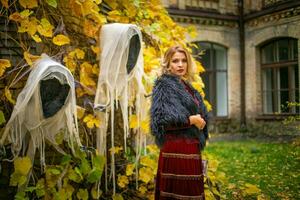 skön kvinna i en häxa kostym står på en bakgrund av spöken. stiliserade halloween dekor. foto