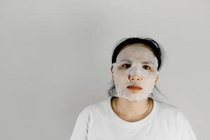 asiatisk kvinna i vit t-shirt och täcker ansiktet med en mask. foto