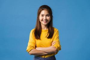 asiatisk dam med positivt uttryck, korsade armar på blå bakgrund. foto