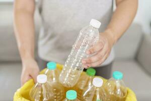 Hem återvinna eco grön noll begrepp man kasta tömma plast flaska i återvinning bin med gul sopor påsar på Hem foto