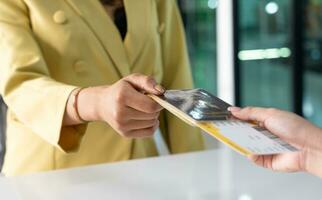 närbild av kvinna händer innehav pass och biljett på flygplats kolla upp i disken foto