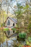 liten kapell i de parkera med reflexion i vatten i våren. foto
