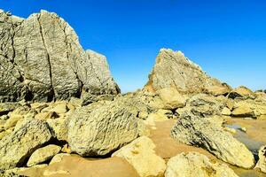 stor stenar på de strand med blå himmel foto