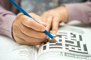 alzheimers sjukdom annons, asiatisk äldre kvinna spelar sudoku pussel spel till öva hjärna Träning för demens förebyggande. foto