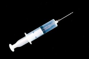 en spruta med en nål på en svart bakgrund foto