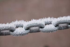 en metall kedja täckt med frost på en pastell bakgrund foto