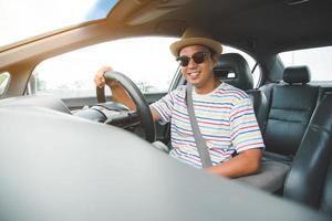 ung stilig asiatisk man som kör bil för att resa. foto