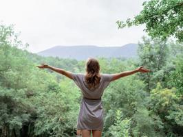 ung kvinna som står på en stor sten i skogen och tittar bort foto