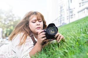 porträtt av överviktig kvinna som tar bilder med en kamera i parken foto