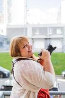 porträtt av överviktig kvinna som tar bilder med en kamera utomhus foto