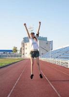 glad sportflicka som hoppar på stadion foto