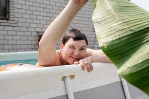 ung man som simmar i poolen och håller ett palmblad