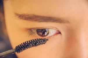 skönhet ansikte av kvinna genom att applicera mascara på ögat med kosmetika. foto