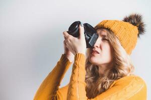 skön flicka fotograf i en stickat hatt Framställ med en kamera i henne händer i en Foto studio