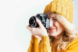 skön flicka fotograf i en stickat hatt Framställ med en kamera i henne händer i en Foto studio