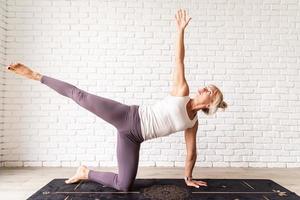 blond kvinna som utövar yoga hemma foto