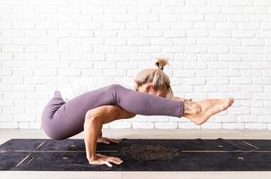 blond kvinna som utövar yoga hemma, gör övningar på mattan foto