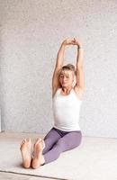 blond kvinna som utövar yoga hemma, stretchar foto