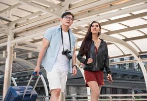 asiatiska par turister ser fram emot och resa i urbana staden. foto