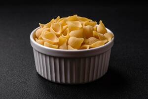 rå italiensk pasta conchiglie från durum vete med grönsaker, salt och kryddor foto