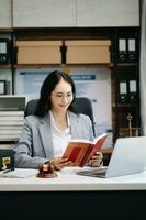 asiatisk kvinna advokat läsning Rättslig bok med klubban på tabell i kontor. rättvisa och lag ,advokat begrepp. foto