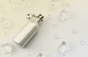 kvinna parfym silverren flaska, mål fotografera av metallisk parfym flaska i is kuber och vatten på vit tabell. se från ovan. attrapp produkt Foto, begrepp av friskhet foto